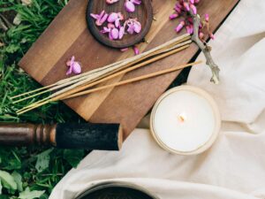 Calming outdoor meditation scene featuring incense, flowers, and a candle on a wooden board.