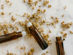 Brown roll-on bottles with dried chamomile flowers on a white background.